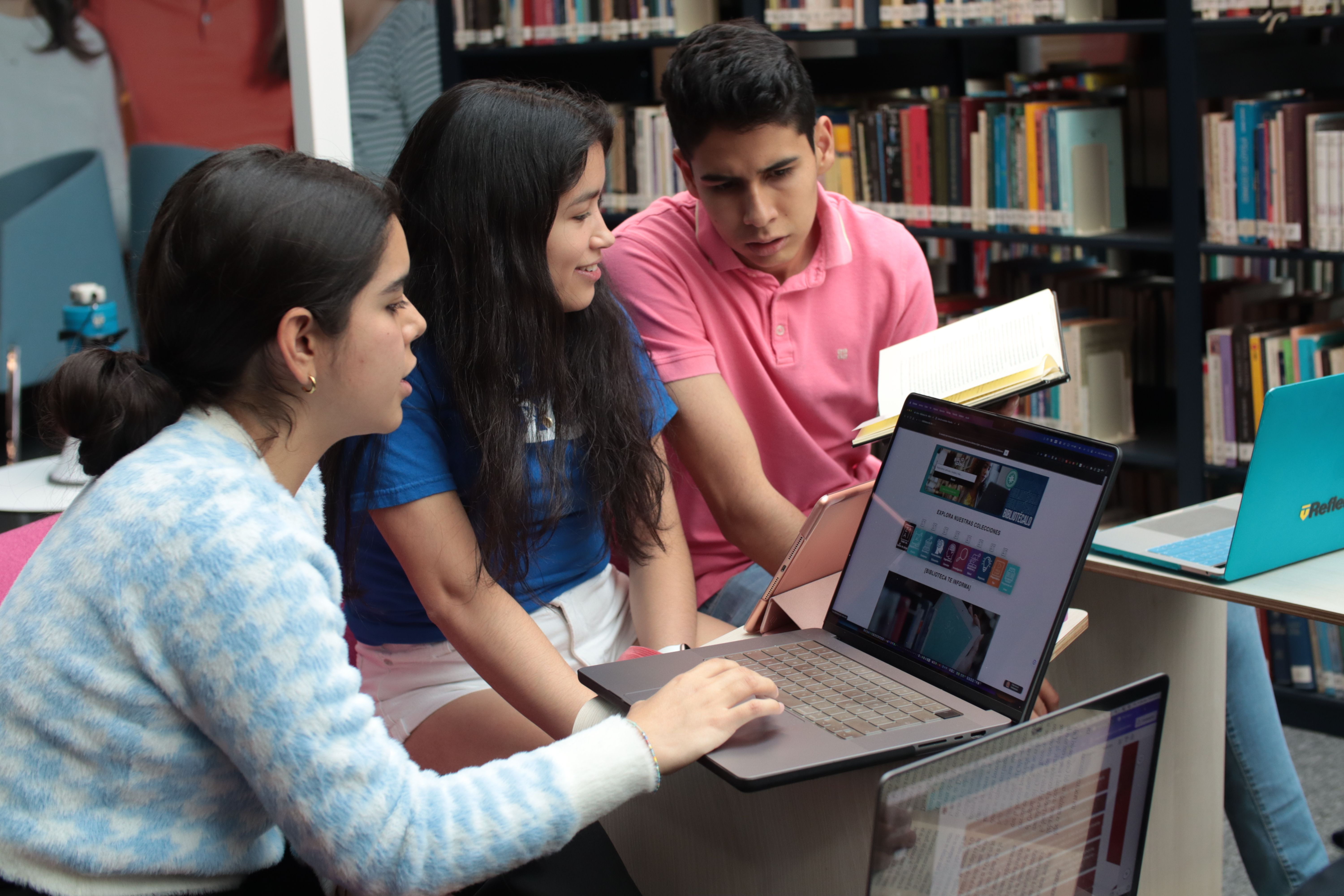 Estudiantes trabajando con laptop en la biblioteca